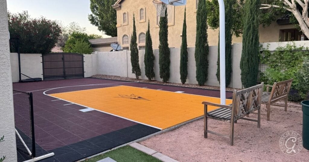 Backyard basketball court with benches, trees, and a yellow and maroon playing surface enhances your backyard layout for both play and relaxation.